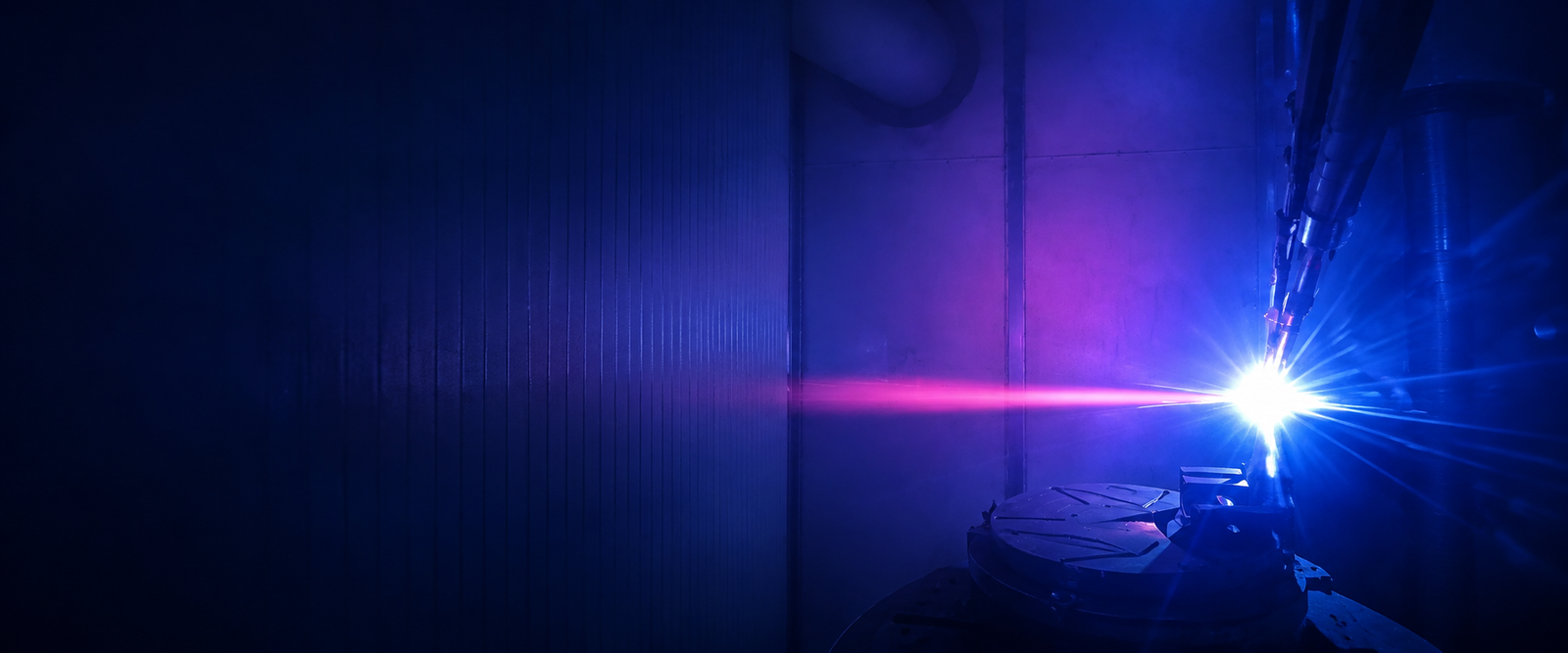 Worker wearing protective gear performing thermal spray in an industrial workshop